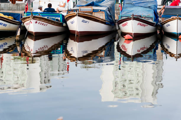 Izmir, Turkey - August  12, 2018: Various fisher boats parked in the shelter with reflection. Bostanli fishing shelter Izmir Turkey.