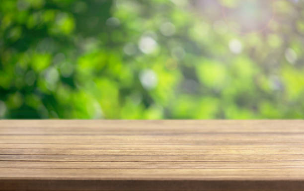 istock wooden table surface and blurred leaves of a tree 1130567195
