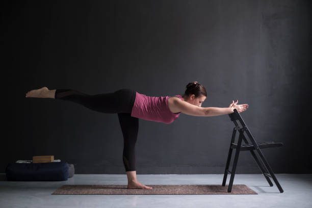 istock Woman show warrior asana using chair in studio background 1130568032