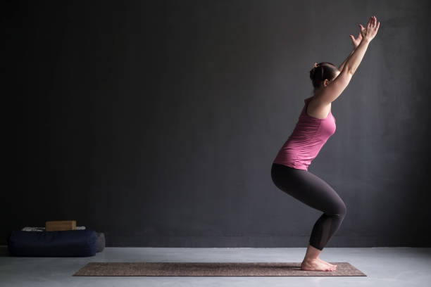 woman practicing yoga, doing chair exercise, utkatasana pose, working out. - one person child serene people failure imagens e fotografias de stock