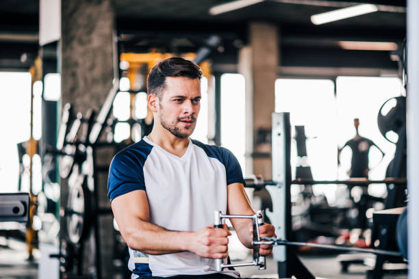 istock Concentrated young man exercising on pull down weight machine in gym. 1130570658