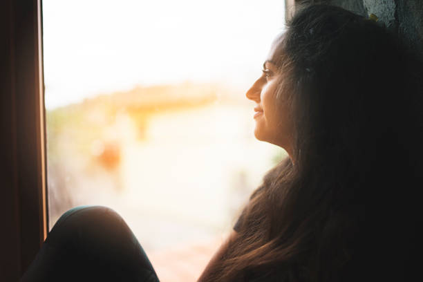 istock Longing woman looking through window at home 1130571241