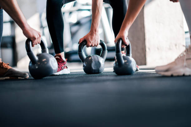 sollevamento pesi, immagine ad angolo basso. atleti con campane del bollitore, primo tempo. - picking up weight women sport foto e immagini stock