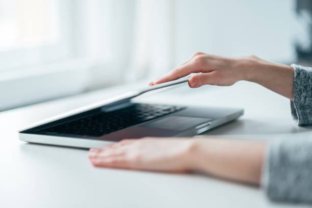 istock Close-up image of female hands open or close laptop on white table. 1130572585