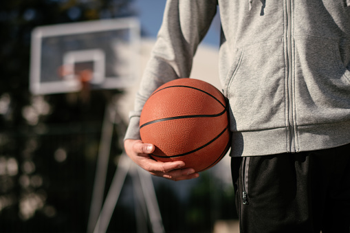 Man holds the ball for basketball. Shallow DOF. Developed from RAW; retouched with special care and attention; Small amount of grain added for best final impression. 16 bit Adobe RGB color profile.