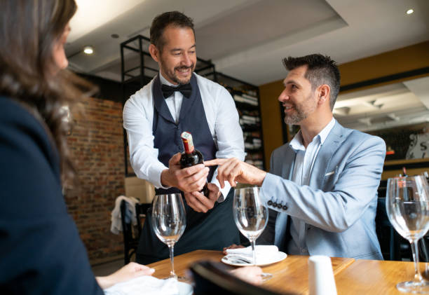 istock Friendly waiter showing male customer the bottle of wine while he points at it both smiling 1130576086