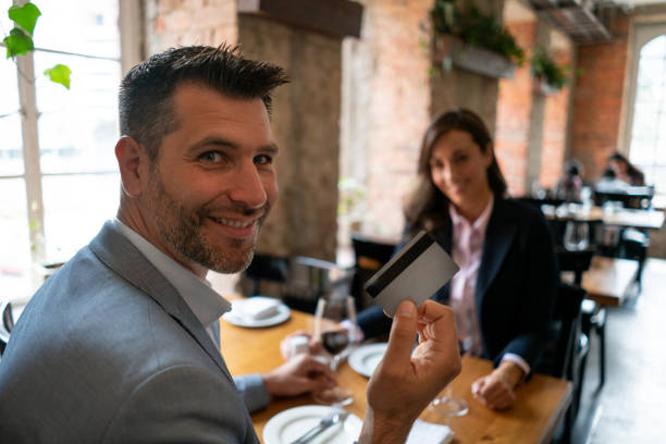 istock Handsome man on a date at a restaurant holding the credit card while facing camera smiling 1130576103