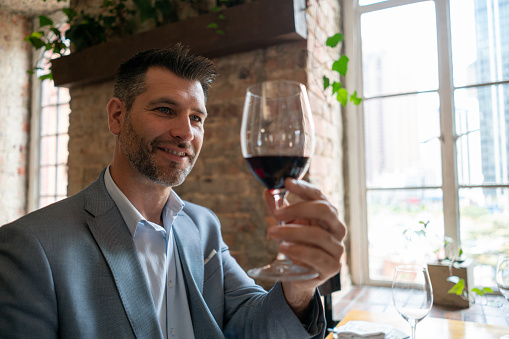 Handsome latin american customer at a restaurant tasting a red wine smiling