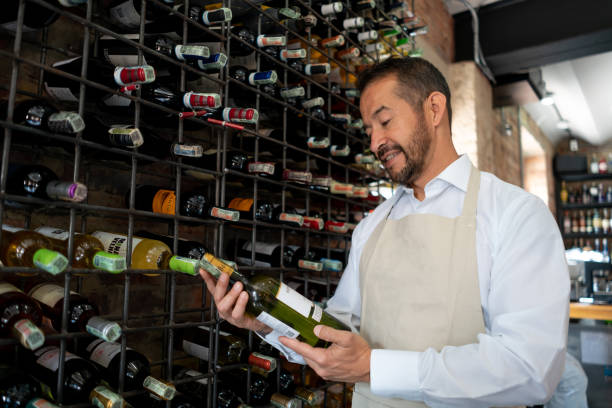 Latin american waiter holding a white wine bottle looking at it