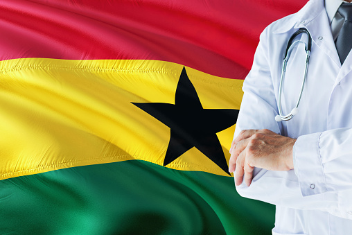 Ghanaian Doctor standing with stethoscope on Ghana flag background. National healthcare system concept, medical theme.