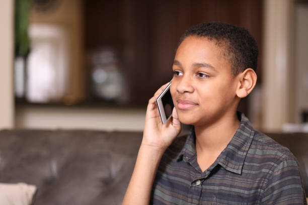 African descent teenage boy using mobile phone at home. stock photo