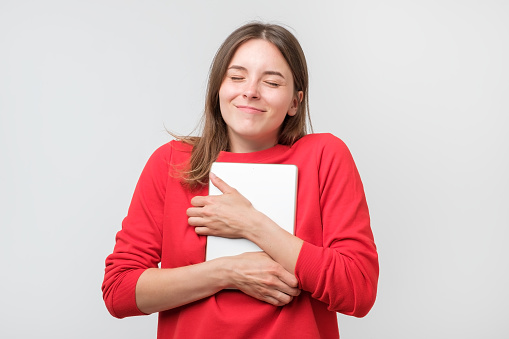 Student hugging laptop. Love to computer concept. Young emotional pretty woman. Human emotions, facial expression