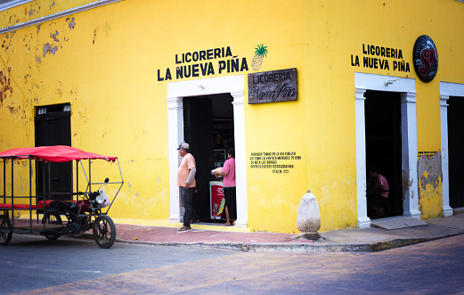 Celestún, Yucatan, Mexico: People in the doorway of a vibrant yellow liquor store in Celestun, a beach village/tourist resort on the Gulf of Mexico about 60 miles from Merida, Yucatan Peninsula.