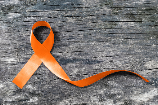 Orange ribbon on old aged background raising awareness on leukemia, kidney cancer and multiple sclerosis