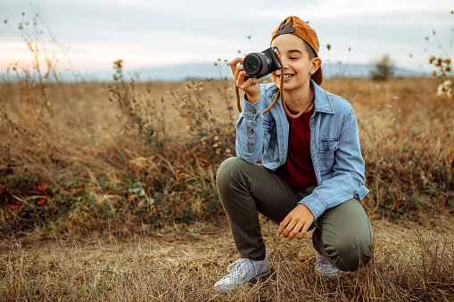 Photo of boy taking photos with camera in nature