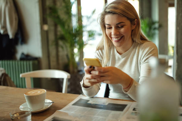 istock Young happy woman text messaging on mobile phone in a cafe. 1130595756