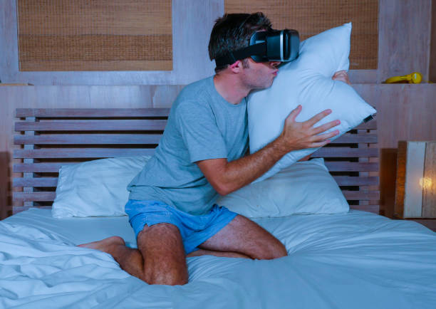 istock young excited and aroused man at home wearing 3d virtual realty goggles having fun on bed playing alone with internet cyber sex VR simulator kissing pillow in sexual illusion and desire concept 1130599295