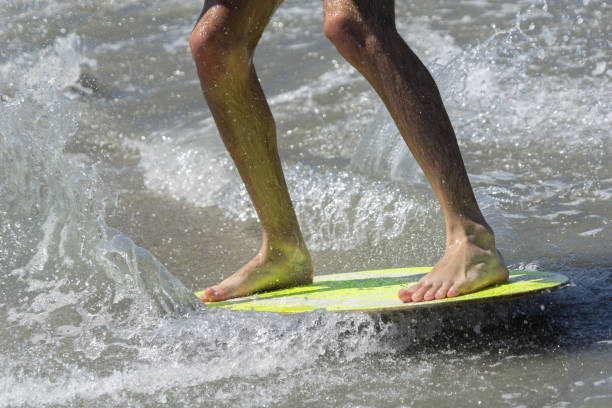 浅い水の中の黄色の基板の脱脂搭乗。 - skimboard ストックフォトと画像