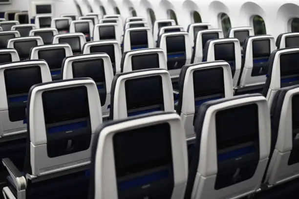 Empty 787 commercial airplane seats viewed from the rear. Inflight entertainment screens