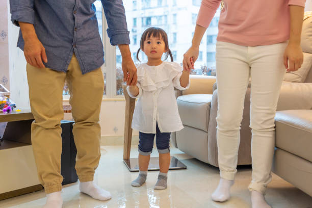 istock Asian Baby Girl Walking While Holding Parents Hands 1130622419