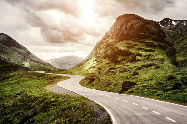 winding mountain road without cars - winding road sunlight field cultivated land imagens e fotografias de stock