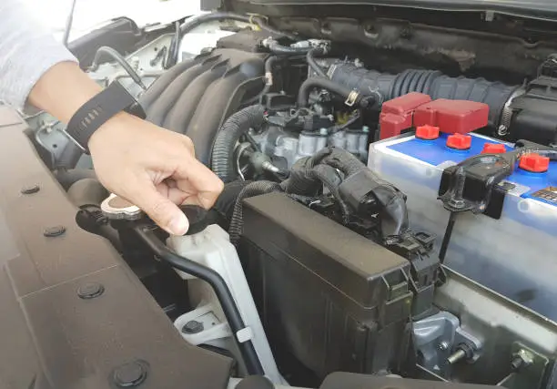 Close up man hand checking the car radiator, engine car. Mechanic with scan tool diagnosing car in open hood.  Selective focus