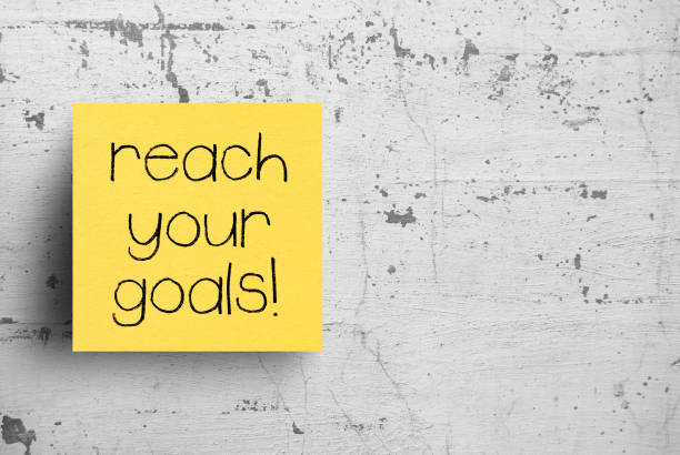 istock Sticky note on concrete wall, Reach Your Goals 1130631350