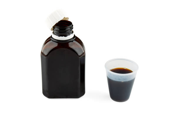 istock Bottle and small plastic glass with brown medicine. Isolated 1130631535