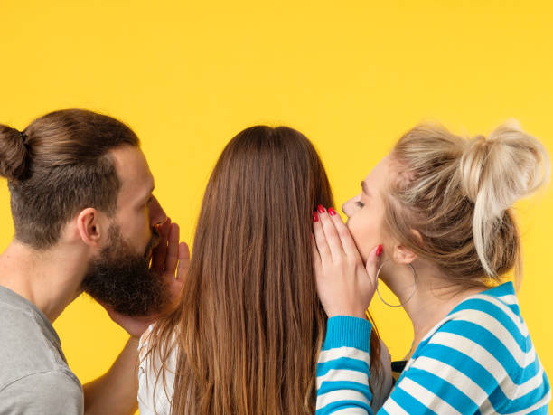 persuasion man woman whisper girls ear Persuasion concept. Man and woman whispering in girls ear. Copy space on yellow background. persuasion photos stock pictures, royalty-free photos & images