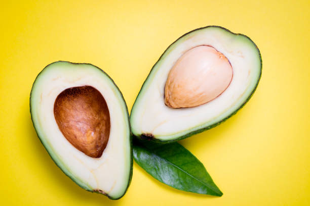 istock Avocado on yellow background. Tropical abstract background with avocado and leaf. Flat lay 1130640280