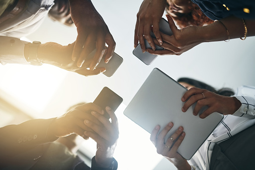 Closeup shot of a group of businesspeople using digital devices in synchronicity in an office