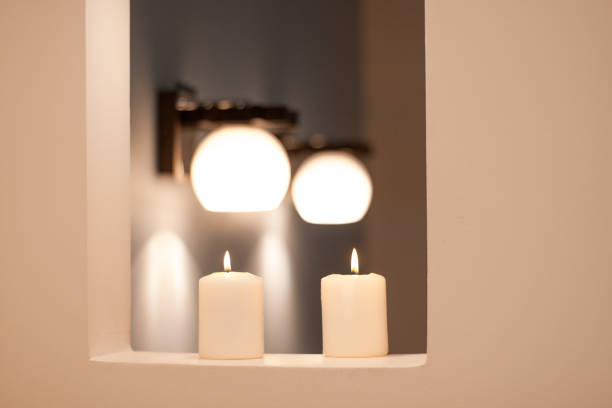 istock Wall lamps with white shade and blurred candles. 1130643100