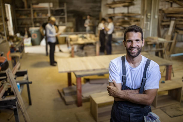 istock Young happy carpenter with crossed arms standing in a workshop. 1130647050