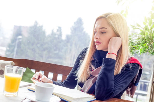 istock Young beautiful woman reading a book in a cafe 1130648659