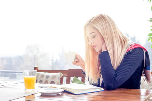 istock Young beautiful woman reading a book in a cafe 1130648668