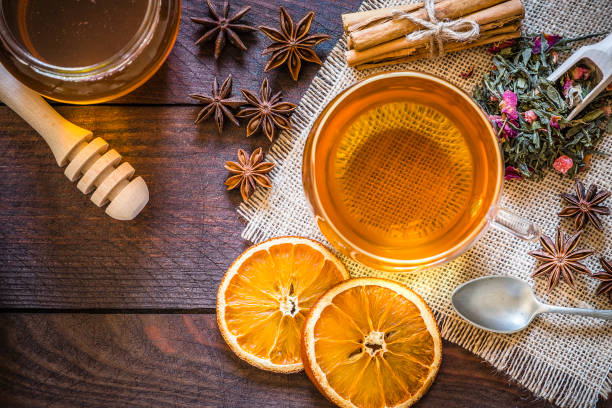 temps de thé: tasse de thé, bâtons de cannelle, anis, orange séchée sur la table en bois - herbal medicine green tea crop tea photos et images de collection