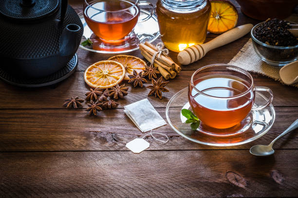 teezeit: tasse tee, zimtstangen, anis, getrocknete orange auf holztisch - teepflanze stock-fotos und bilder