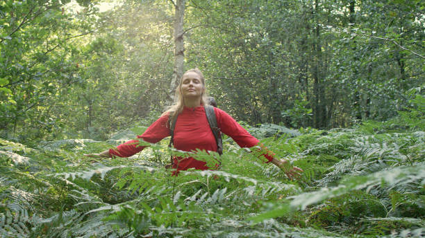 istock Woman exploring glade with ferns. Open arms 1130649096