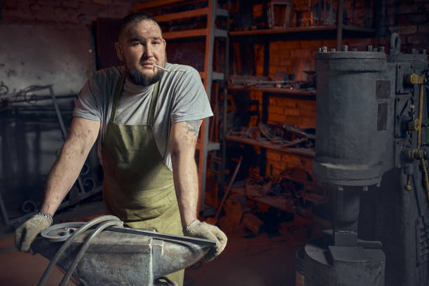 handsome blacksmith guy with muscular body, wearing gloves for safety, isolated in workshop