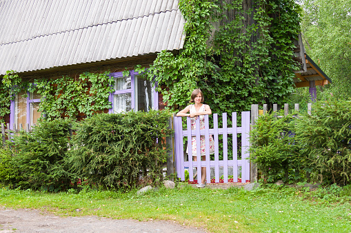 Young positive female in a dress posing on her country house garden in summer