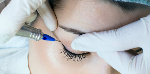istock Cosmetologist applying permanent make up eyeliner, eyeliner tattoo procedure 1130659256