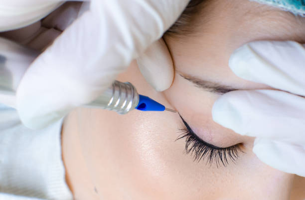 istock Cosmetologist applying permanent make up eyeliner, eyeliner tattoo procedure 1130659262