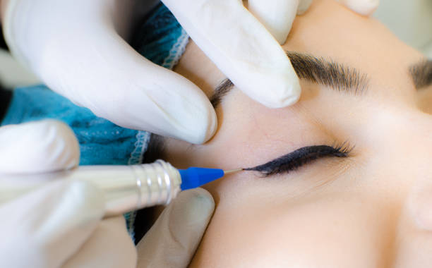 istock Cosmetologist applying permanent make up eyeliner, eyeliner tattoo procedure 1130659318