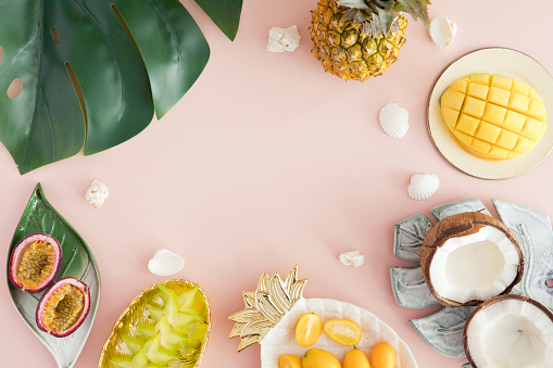 Frutas exóticas en fondo rosa pastel-piña, mango, coco, carambola, maracuyá. Vista superior y flatlay photo