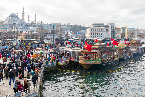 Istanbul, Turkey - Feb 01, 2019: Eminonu district with many facilities to eat such as floating restaurants and carts with fresh bakery, hot corn or roasted chestnuts in Istanbul, Turkey.