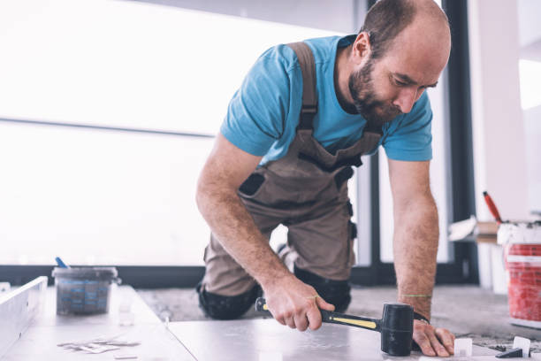 istock Professional tiler fixing newly installed tiles with rubber hammer 1130660591