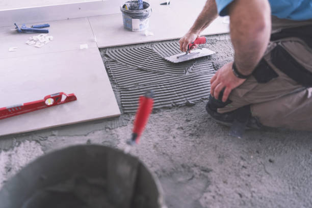 Man applying tile adhesive on the floor Cropped image of adult builder spreading and smoothing tile adhesive on the floor kneepad stock pictures, royalty-free photos & images