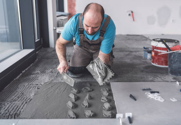 istock Adult mason spreading tile adhesive on the floor 1130660596