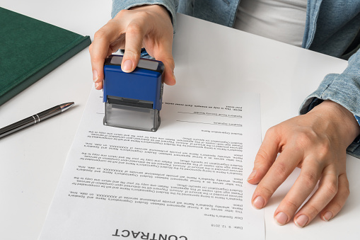 Business woman putting stamp on documents in the office - signing contract concept