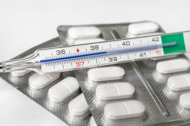 istock Close-up of mercury thermometer with pills on background 1130662641